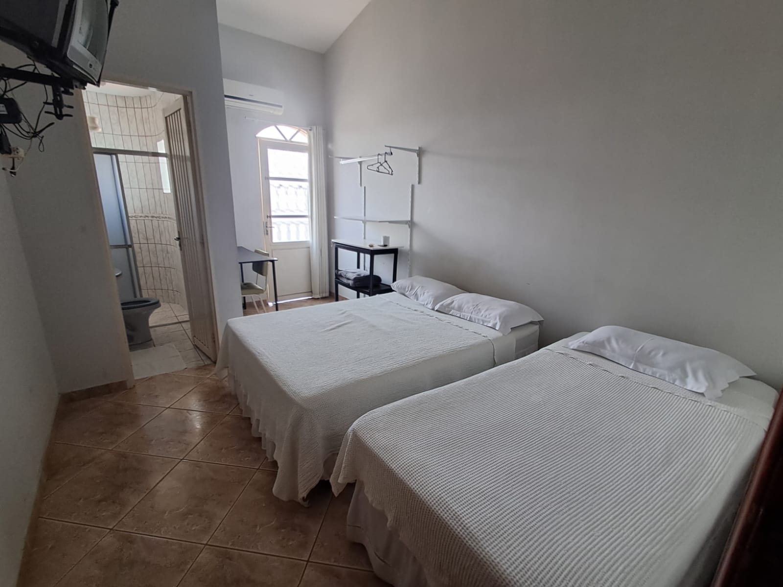 Quarto com duas camas de solteiro e televisão